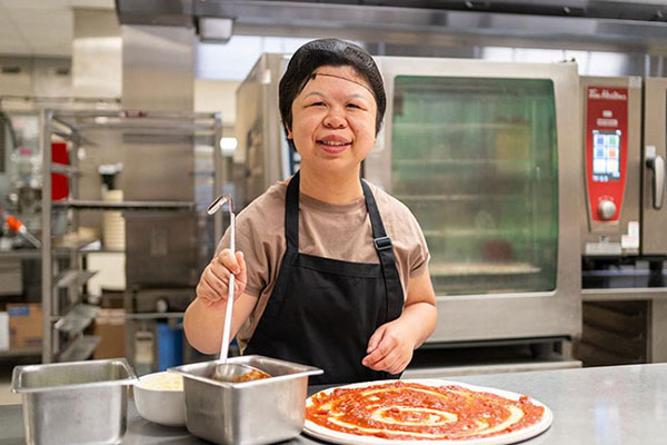 An adult making pizza in a kitchen setting
