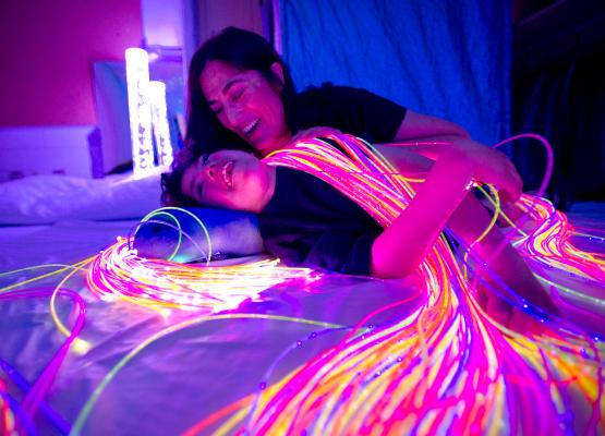 Mother and teen in dim light with fibre-optic lights draped on them