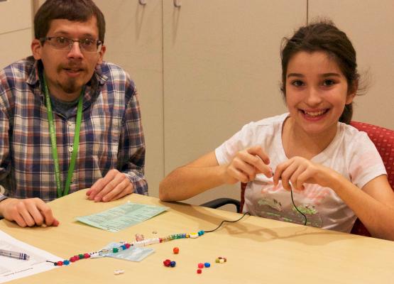 Child life specialist helps girl make bravery bead necklace