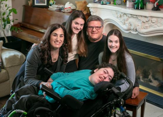 Young man in a wheelchair surrounded by sisters and parents