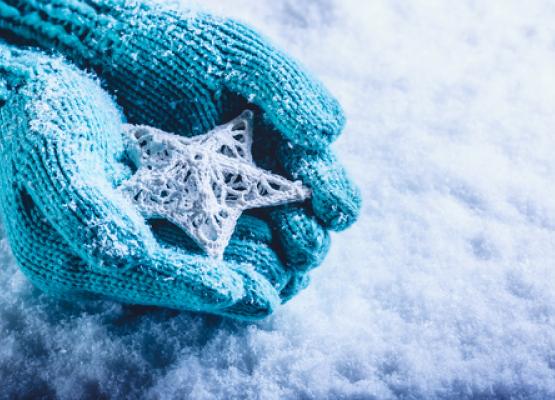 Light blue knitted gloves hold a detailed snowflake