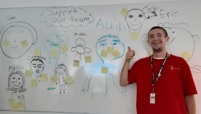 Student standing in front of a whiteboard that says Support Your Team.