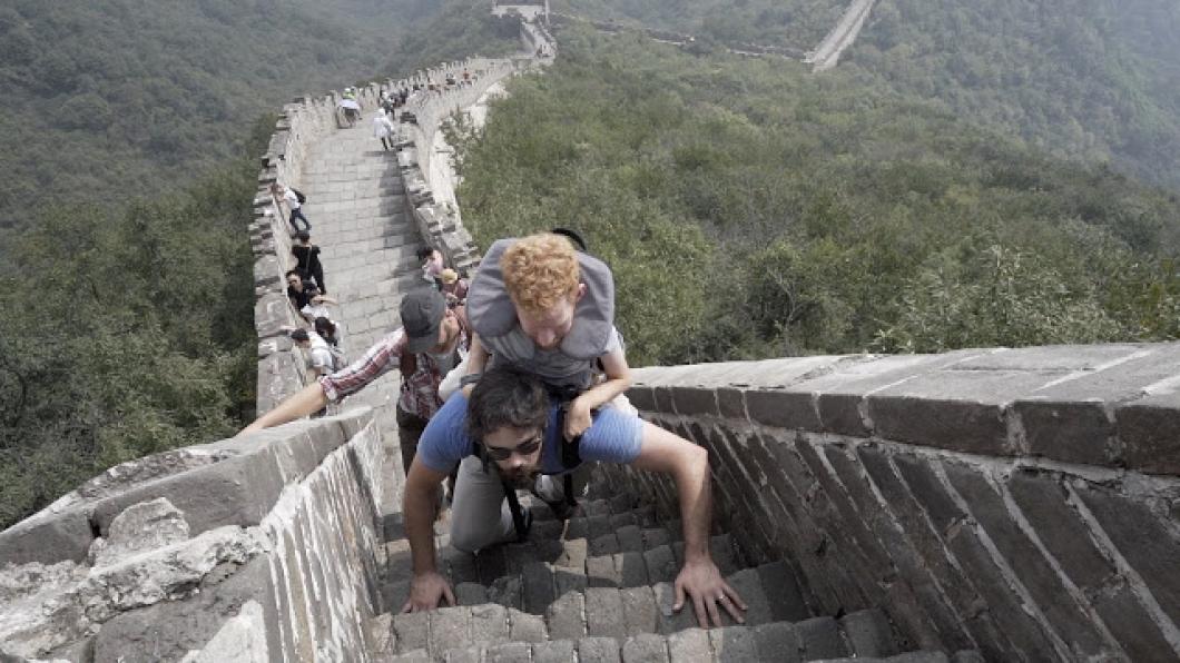 Man being carried in backpack by another man on the Great Wall of China