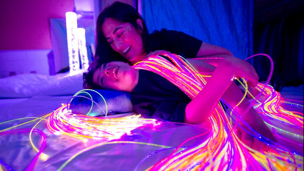 Mother and teen in dim light with fibre-optic lights draped on them