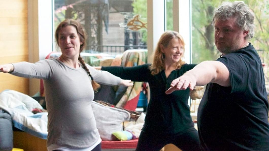 Three adults do a yoga pose