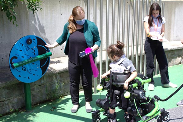 Two adults and a kid on wheelchair playing in an outdoor setting