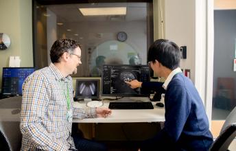 Two adults looking at an image of a brain scan on a computer screen