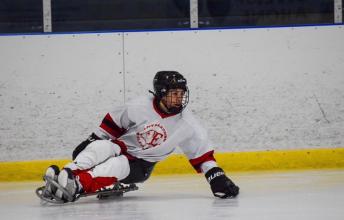 A young boy plays sledge hockey.