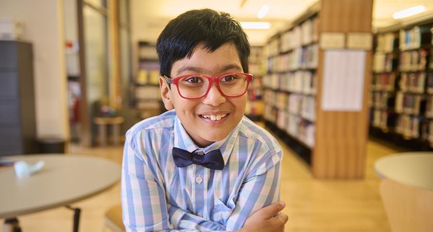 A child with smile sitting in a library setting