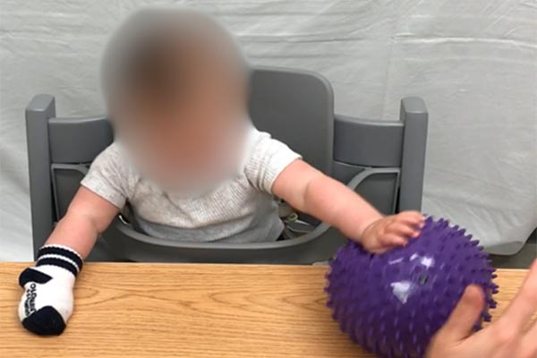 Have the infant push a ball, rolling it on a table with a straight elbow. 