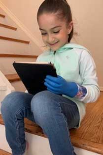 A girl using her left hand with a machine on to hold a tablet