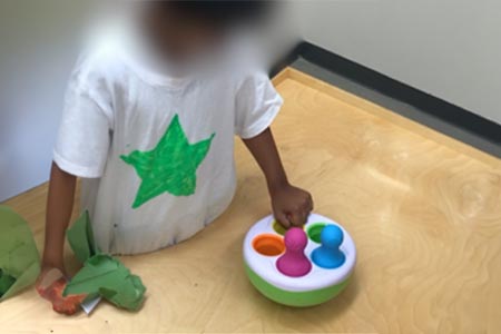 Give cause and effect toys (e.g., toy that lights up, makes sound, vibrates) to encourage the infant to stabilize the toy on a surface by using their hand (hand can be fisted).