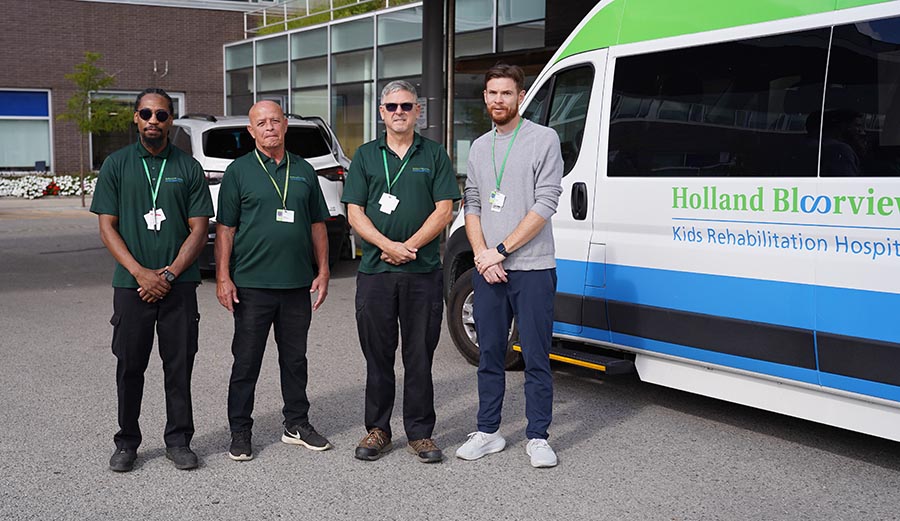 Four people standing in front of a mini bus
