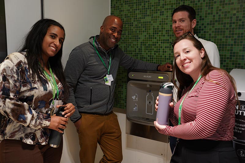 Four adults standing in front of a water fountain machine