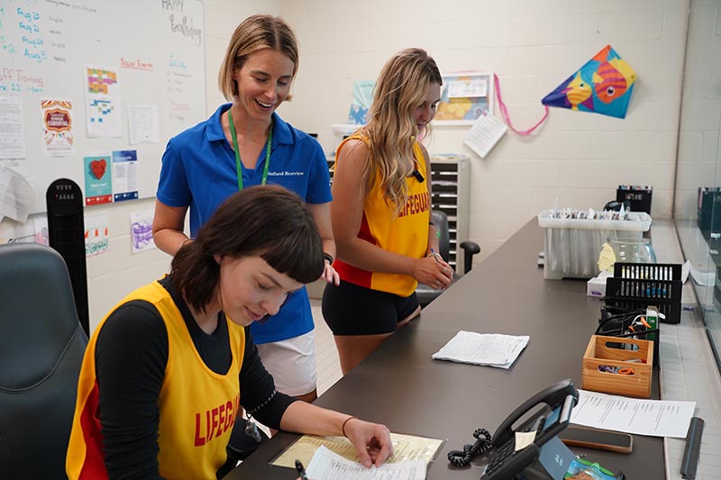 Two lifeguard and a staff discussing about schedule of a swimming pool