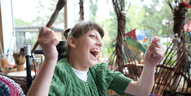 Girl in wheelchair laughing in the art room.