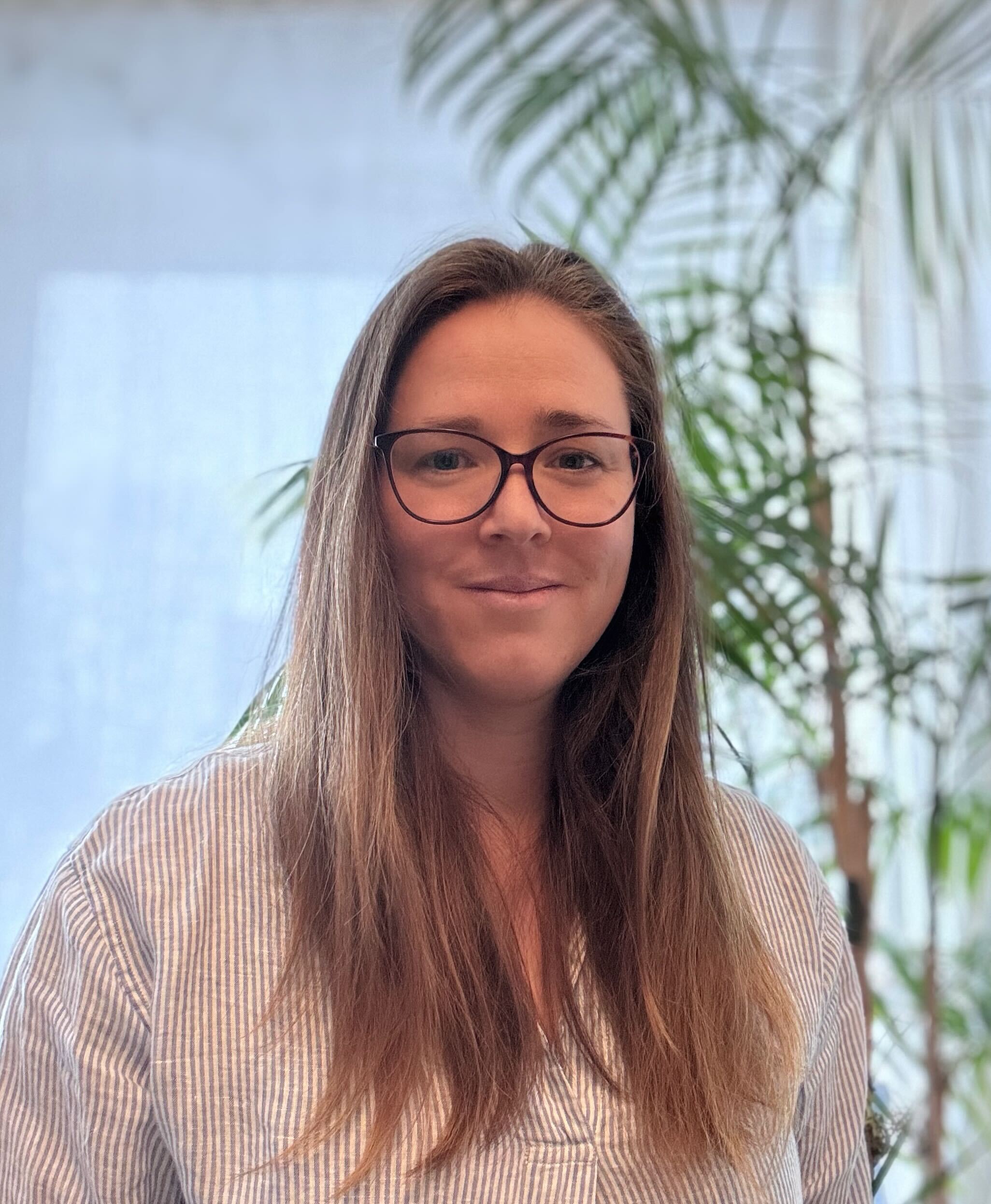 Woman with black rimmed glasses, striped shirt and medium length brown hair