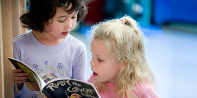 Two little girls reading a book.