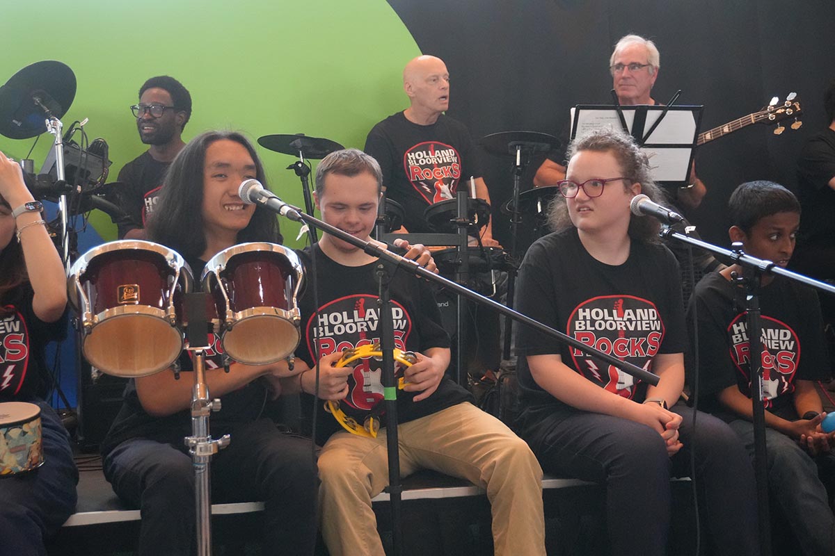 HB Rocks performers share a moment together during the concert, surrounded by their bandmates.