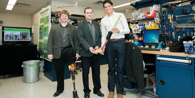 Three men in a lab. One with prosthetic knee and two scientists.