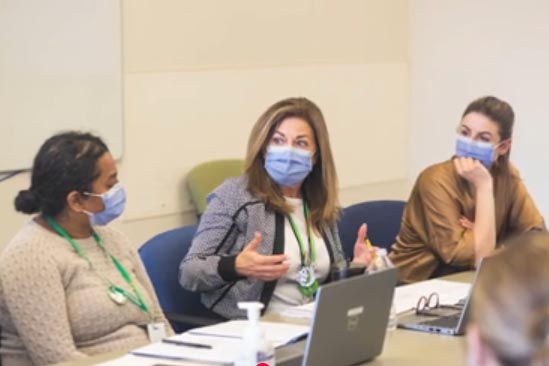 A group of people with their masks on, in a meeting.