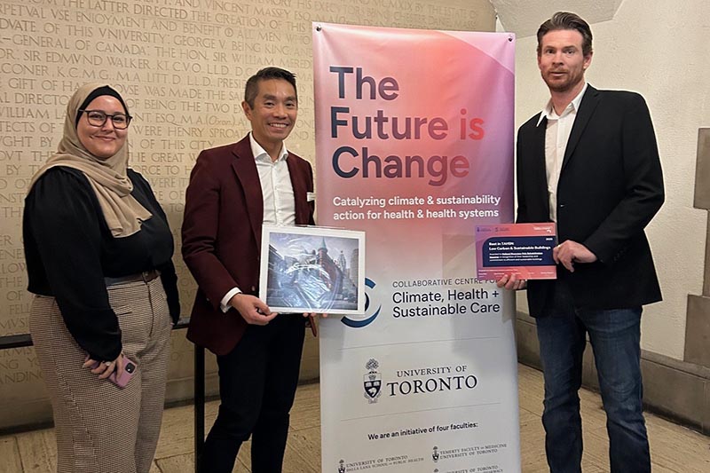 Three people in front of a "the future is change" flag