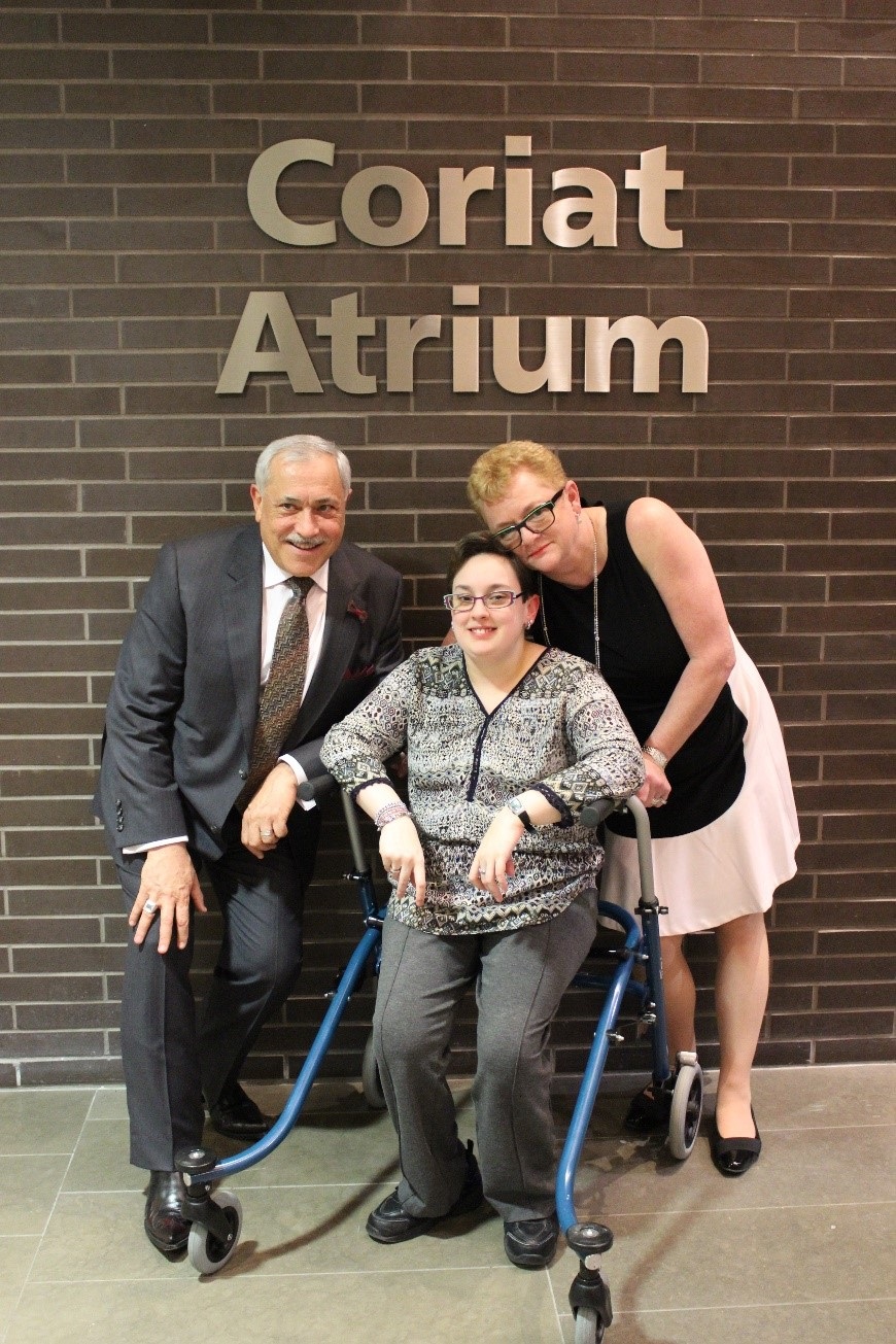 The Coriat Family posing in front of a wall with a sign that says "Coriat Atrium" in silver letters.