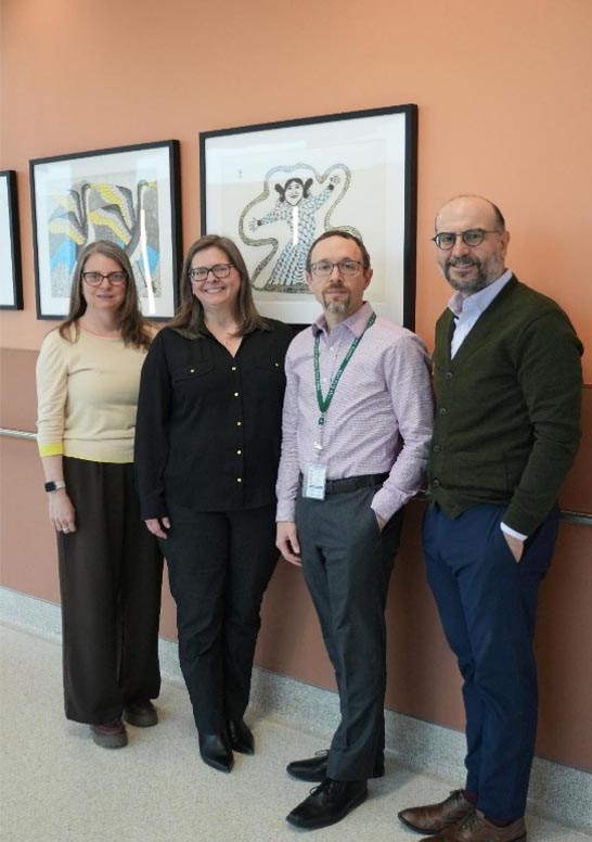 Four people standing in front of some paintings