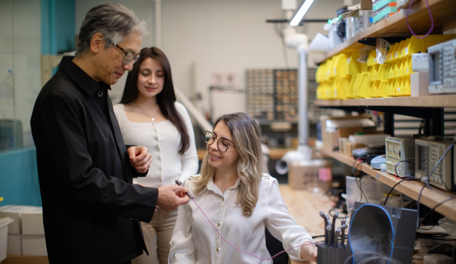 Researchers conferring at electronics workbench