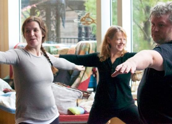 Three adults do a yoga pose