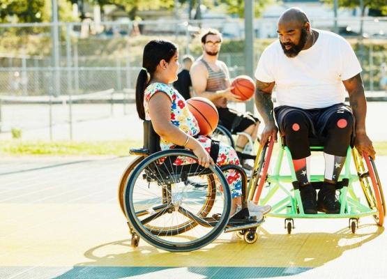 Man and girl in wheelchairs playing basketball