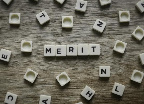 The word merit spelled with Scrabble pieces