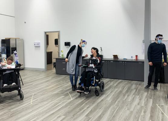 Three young adults in wheelchairs with staff wearing masks and shields