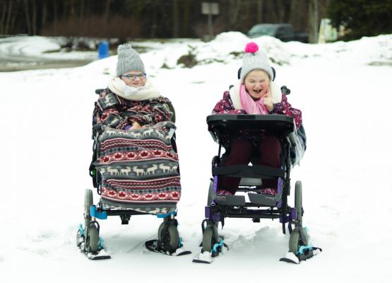 Girls in wheelchairs with mini skis under the wheels