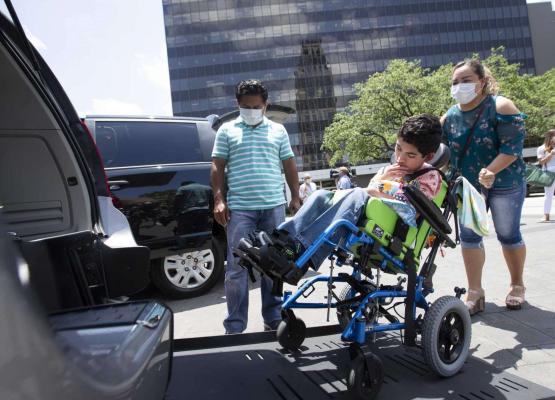 Mother pushing son in wheelchair into accessible van