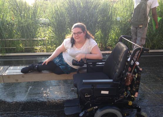 Smiling woman lounging on bench with wheelchair to the side