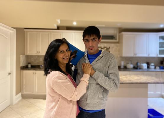 Mother with arms around young adult son in the kitchen