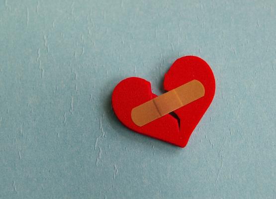 Broken red heart with bandage on blue background