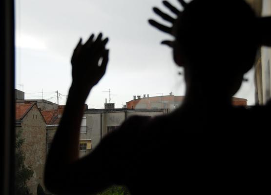 Silhouette of woman with hands on the window looking out