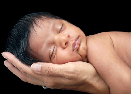 Image of newborn with black hair lying on mother's hand