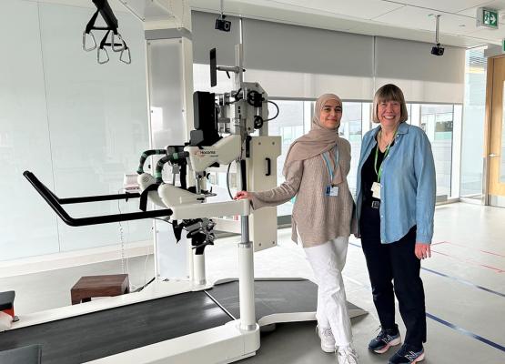 Two women stand in front of a robotic treadmill