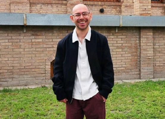 Man wearing glasses with white collared shirt and blue jacket smiles