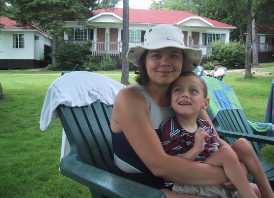 Woman with white sun hat in beach chair holding young boy