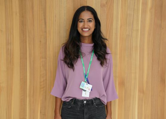 Woman with long dark hair and purple shirt wearing a green lanyard