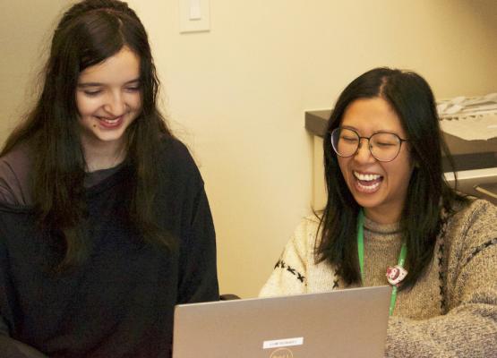 Teen girl and woman laugh at computer screen