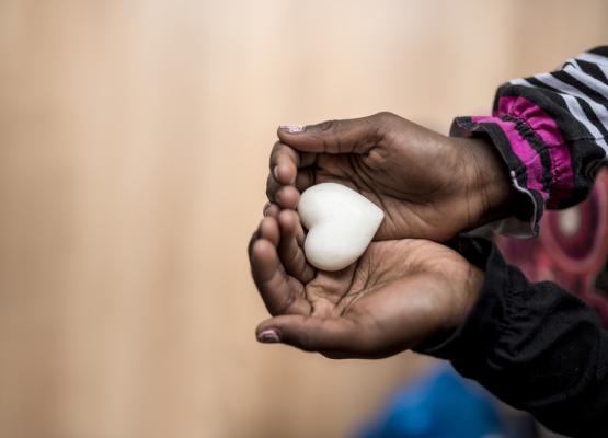 Hands hold a white heart shaped object