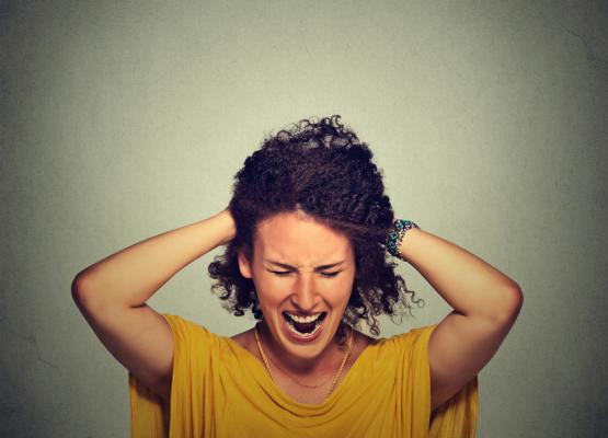 Woman grabs hair and grimaces