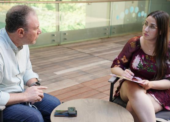 Woman with clipboard sits across from man