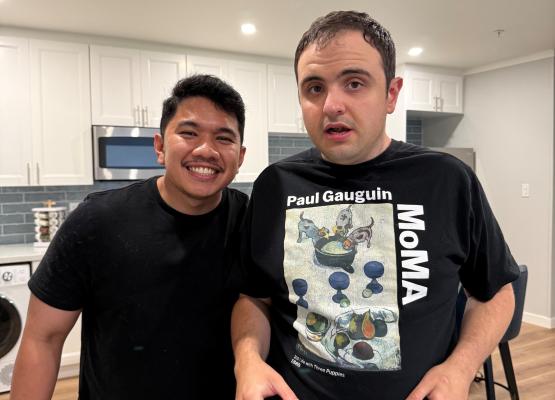 Two young men with kitchen behind them