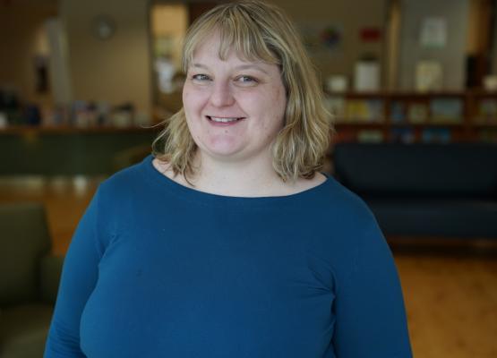 Woman with blonde hair and blue sweater in library